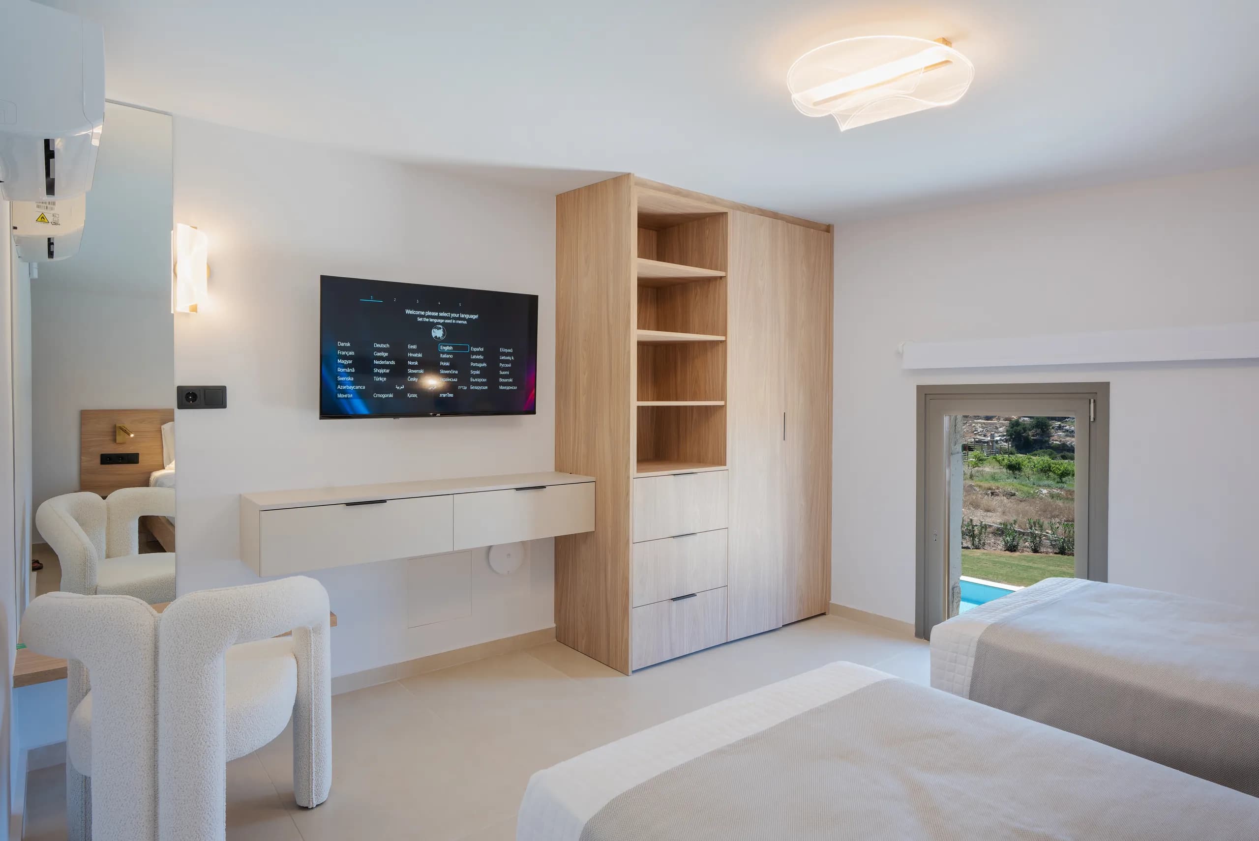 A spacious Left Crete bedroom with a desk, television and natural timber cabinetry