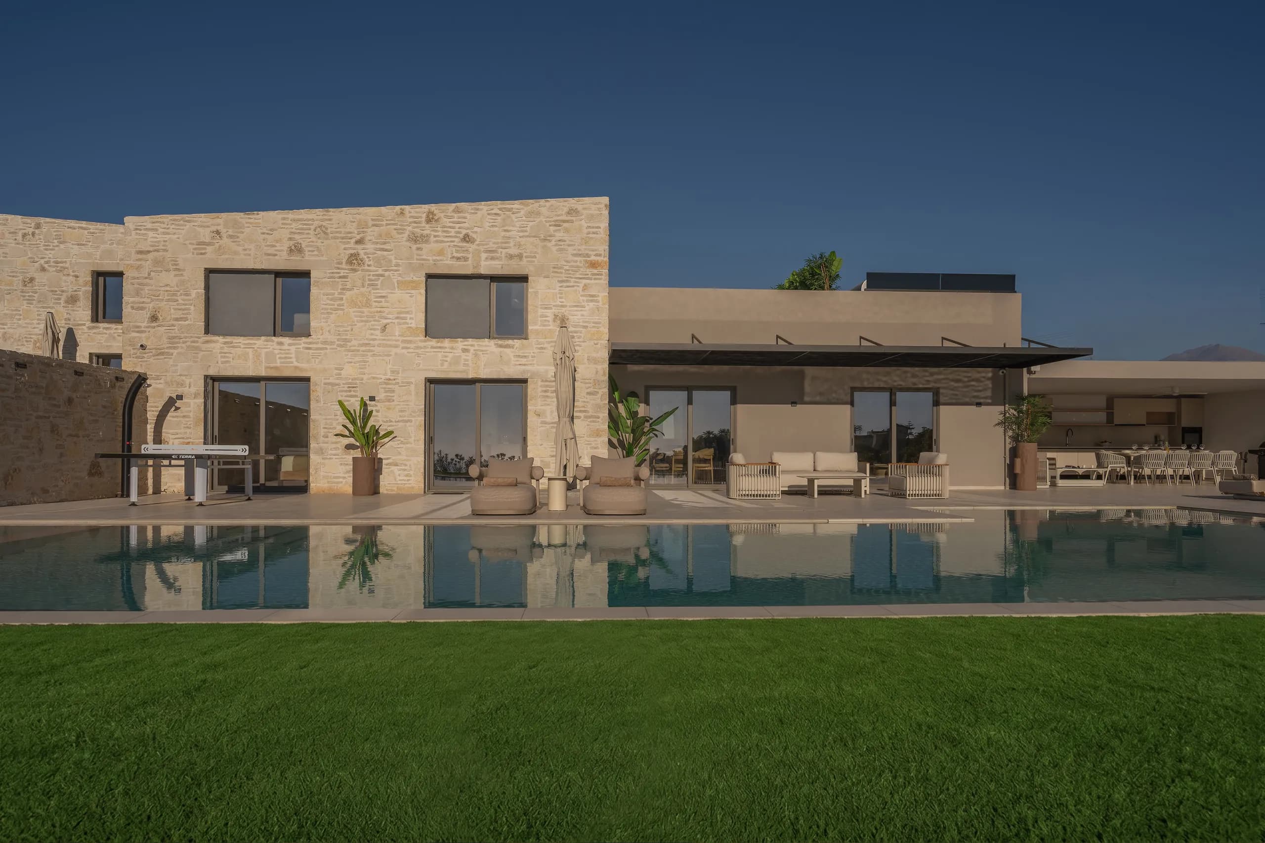 The stone facade and outdoor living spaces of Left Crete reflected in its pool